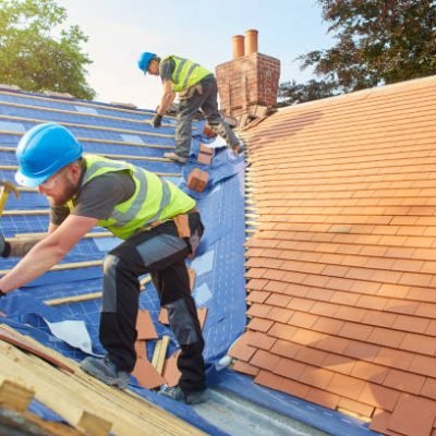 a roofer nails on the roof tiles